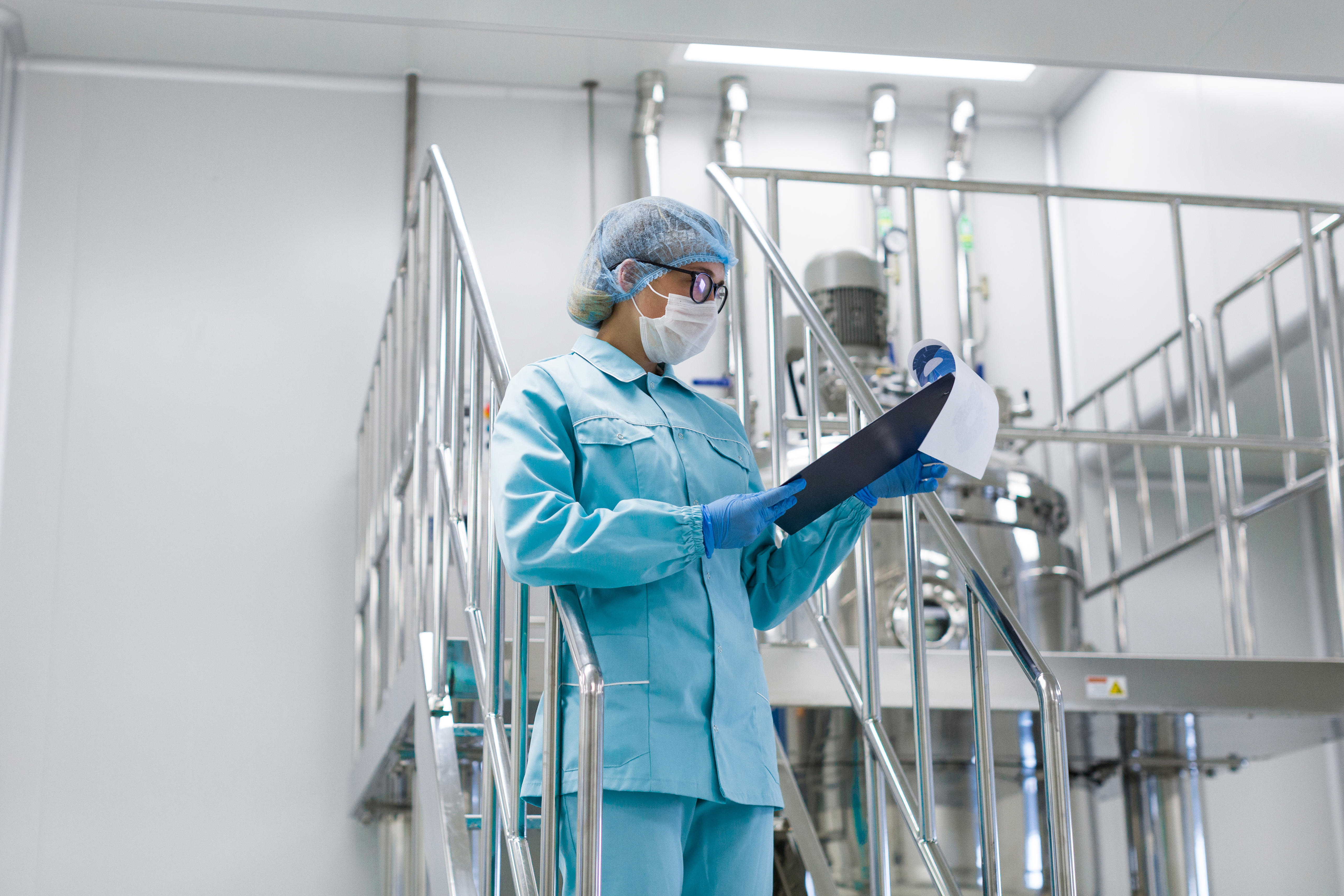 Cleanroom technician reviewing validation documentation on clipboard inside pharmaceutical facility